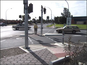 Signalized left 
              turn lane with APS mounted close to the crosswalk locations. Three 
              APS are on the splitter island, one for each crossing.